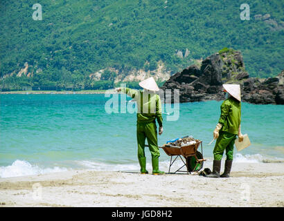 Due pulitori sono la pulizia della magnifica spiaggia in Vietnam. Tropici, il Mare della Cina del Sud. Foto Stock
