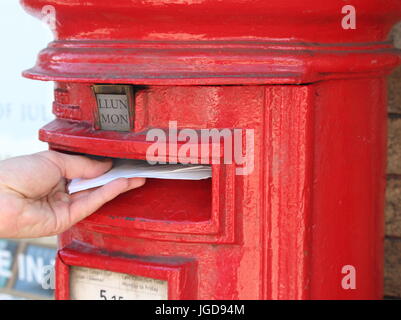 Un maschio lato inviare una lettera in una buca delle lettere che ha bilingue (gallese e inglese) segnaletica. Abergavenny, Regno Unito. 2 Luglio 2017 Foto Stock