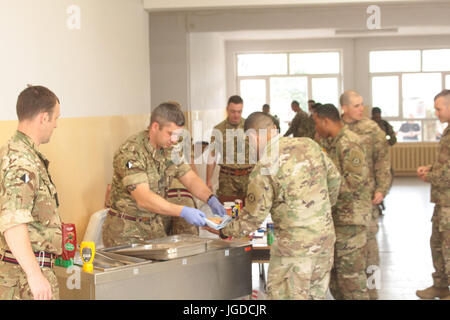 Soldati statunitensi, britannici e rumeni in servizio con la 15th Mechanized Brigade polacca hanno partecipato ad attività morali tra cui concessioni e proiezioni di film presso la Bemowo Piskie Training area il 30 giugno 2017, sostenendo la missione Enhanced Forward Presence Deterrence della NATO nel nord-est della Polonia. Foto Stock