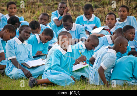 Kenia Masai Mara - Luglio 18, 2008: scuola gli studenti sedersi sulla terra e aspettare il bus di scuola. Foto Stock