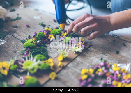 Fioraio effettuare decorazioni di fiori con lettere e colla. In interni luce naturale shot con piccole profondità di campo Foto Stock