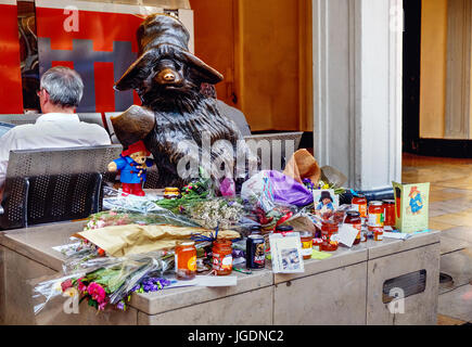 Vasi di marmellata di arance, le carte e i fiori di cui alla statua di Paddington Bear, presso la stazione di Paddington, a seguito della morte di Michael Bond. Foto Stock