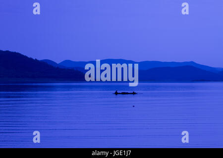 Silhouette pescatore con net presso il lago in Thailandia Foto Stock