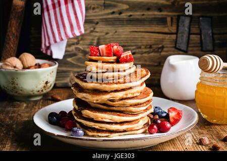 Tutto pasto pancake con frutti di bosco freschi e miele sul tavolo di legno. Primo piano. Stile rustico stock foto di cibo Foto Stock