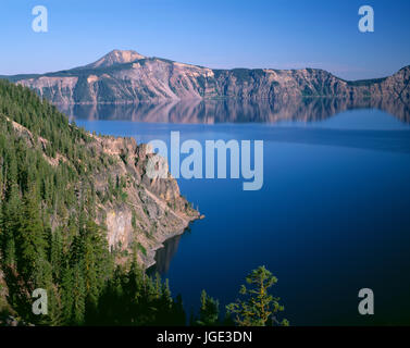 Stati Uniti d'America, Oregon, il Parco nazionale di Crater Lake, foresta di conifere sopra la baia di acciaio sul lato nord del cratere del lago e distante Monte Scott. Foto Stock