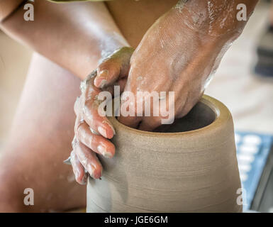 Le mani di un vasaio sagomatura di un vaso su un tornio del vasaio. Foto Stock