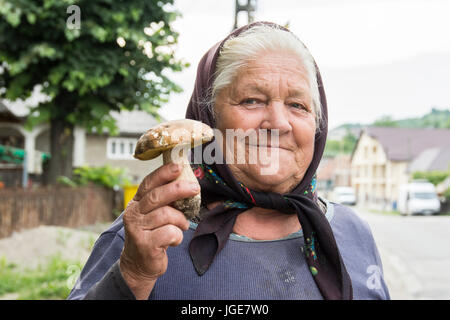 Una vecchia donna mostra un fungo nella regione Maramures, Romania Foto Stock