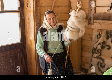 Una donna la filatura della lana con un metodo tradizionale della regione Maramures, Romania Foto Stock