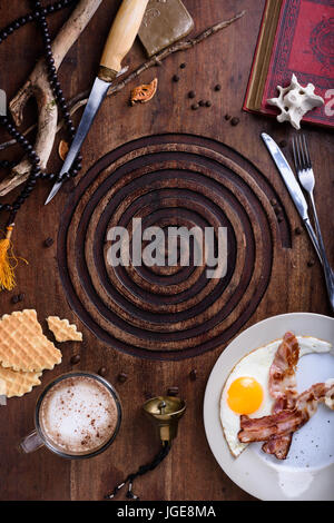 La prima colazione di pancetta e uova fritte con latte il caffè sul tavolo antico. Cacciatori vintage stile capanna. Vista superiore, alimentare il telaio. Foto Stock