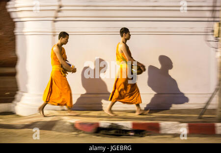 I monaci a piedi lungo la parete del tempio a Luang Prabang, Laos Foto Stock