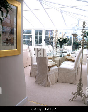 Sedie con bianco copre allentati al tavolo di vetro in Conservatorio sala da pranzo in conservatorio Foto Stock