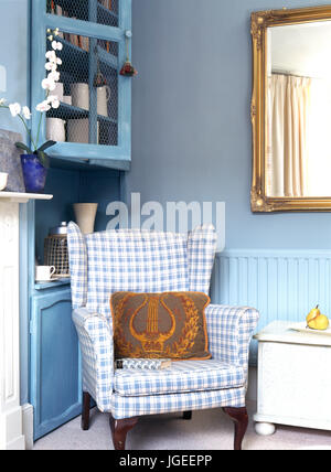 Blue+bianco a scacchi sedia imbottita accanto al piccolo comodino con  lampada accesa nella camera da letto con il blu+white biancheria da letto  Foto stock - Alamy
