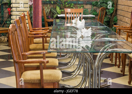 Interno di un vecchio ristorante con vecchie sedie di legno e tavoli di vetro. Foto Stock