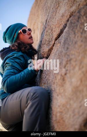 Giovane donna caucasica arrampicata su roccia nel deserto vestito per basse temperature Foto Stock