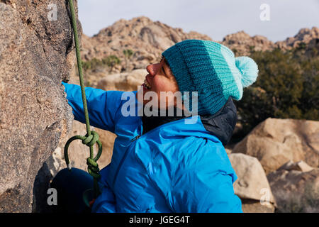 Giovani razza mista donna vestita per basse temperature salite di roccia nel deserto Foto Stock