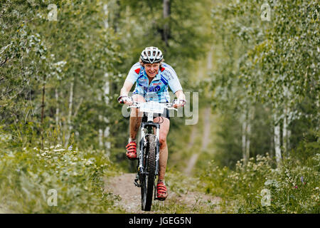 Giovani femmine ciclista a cavallo, lungo un sentiero forestale durante i campionati regionali in mountain bike Foto Stock