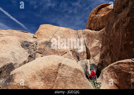 Giovani razza mista donna rock si arrampica nel deserto con attrezzatura tecnica mentre vestita per basse temperature Foto Stock