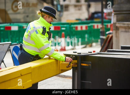 Un funzionario di polizia si chiude la barriera all'Admiralty Arch a Trafalgar Square a Londra installato a seguito di una serie di attentati terroristici che coinvolgono veicoli. Foto Stock