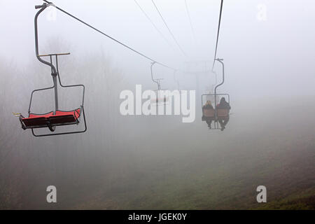 Nelle prime ore del mattino, un sollevamento di montagna porta i turisti per un sonno di montagna, avvolta in una fitta nebbia Foto Stock