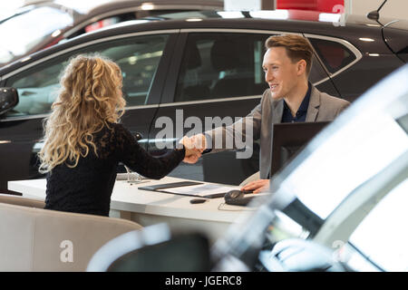 Sorridente venditore facendo handshake con il cliente femmina Foto Stock