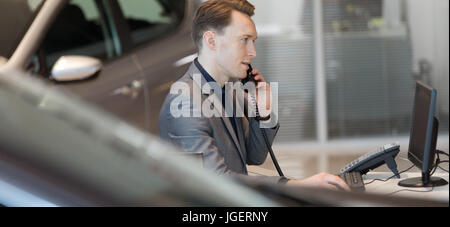 Venditore parlando al telefono di rete fissa in showroom Foto Stock