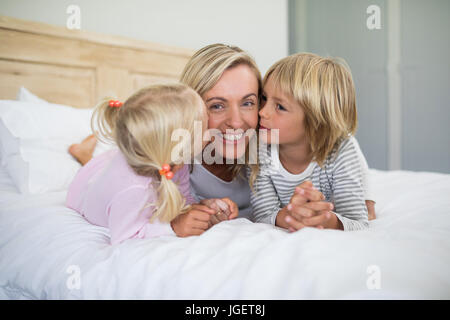 I fratelli kissing madre sulle sue guancie nella camera da letto di casa Foto Stock