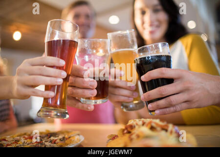 Basso angolo di vista happy amici tostare le bevande al tavolo nel ristorante Foto Stock