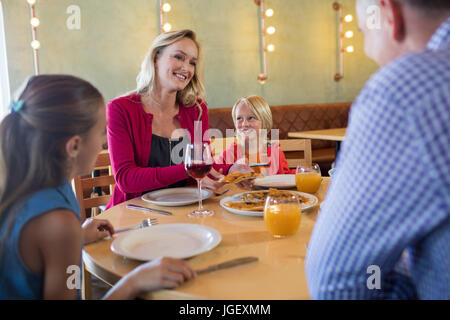 La famiglia felice di parlare mentre godendo antipasto in ristorante Foto Stock