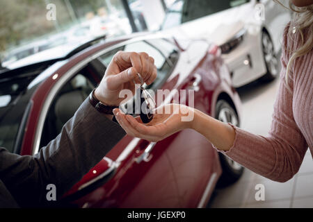 Chiusura del venditore di dare le chiavi dell'auto al cliente femmina Foto Stock