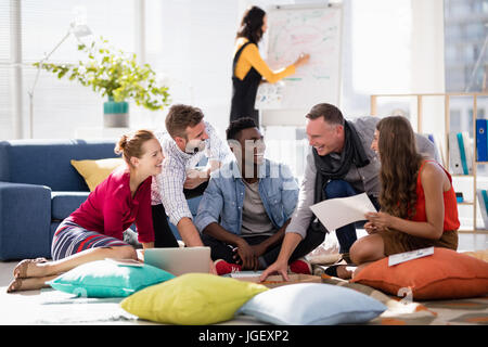 Team di colleghi di lavoro avente la pizza insieme mentre si lavora in ufficio Foto Stock
