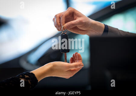 Immagine ritagliata del venditore dando chiave auto al cliente Foto Stock