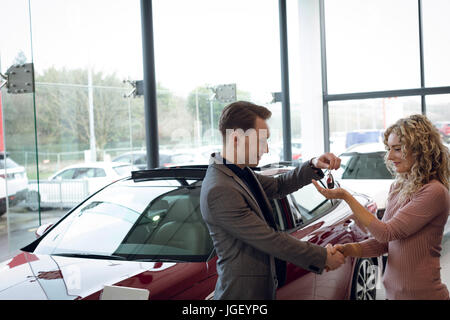 Venditore handshake facendo mentre dà le chiavi per il cliente Foto Stock