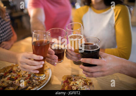 Mani tagliate di amici tostare le bevande al tavolo nel ristorante Foto Stock