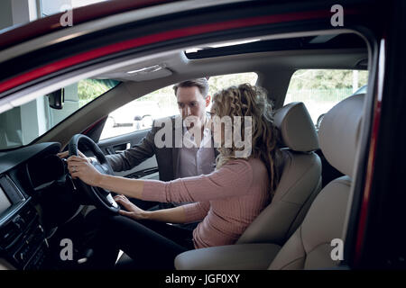 Addetto alle vendite assiste donna seduta in auto Foto Stock