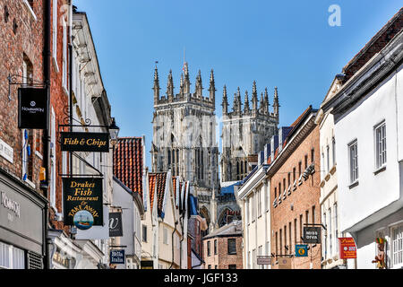 Negozi, segni e le torri della cattedrale di York Minster (la Cattedrale Metropolitical e Chiesa di San Pietro in background, York, nello Yorkshire, Inghilterra, Regno Unito Foto Stock