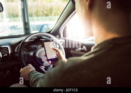 Sezione mediana dell'uomo utilizza lo smartphone in auto Foto Stock
