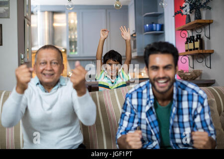 La famiglia felice clenching pugno mentre si guarda la partita di calcio a casa Foto Stock