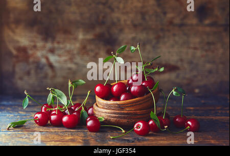 Le ciliegie in una ciotola su una tavola di legno. Appena raccolto le ciliegie in una ciotola su una tavola di legno. Foto Stock
