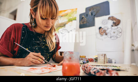 Colpo di bella giovane artista femminile pittura in studio. Donna pittore disegno sulla carta nella sua officina. Foto Stock