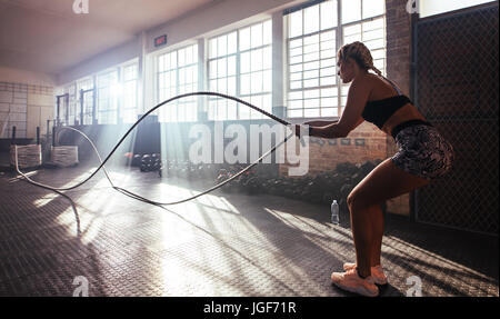 Donna di sollevamento pesi pesanti in palestra per allenare la muscolatura. Atleta esercizio utilizzando una barra di peso. Foto Stock