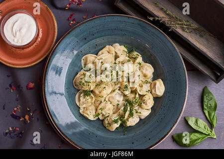 Vista ravvicinata di bollito in casa gnocco di carne servita in creta blue plate con salsa cremosa. Composizione in stile rustico su sfondo di legno Foto Stock