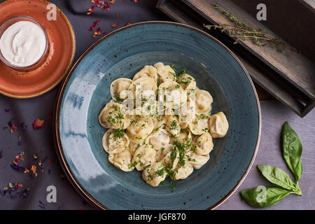 Vista ravvicinata di bollito in casa gnocco di carne servita in creta blue plate con salsa cremosa. Composizione in stile rustico su sfondo di legno Foto Stock