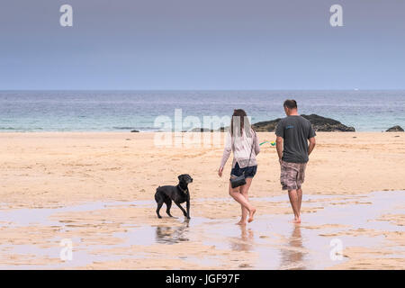 Persone su una spiaggia. Per i turisti e il loro cane a camminare lungo la spiaggia di Harlyn Bay in Cornovaglia. Foto Stock