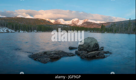 Le montagne ricoperte di neve può essere visto da ratti Sprague lago su una mattina di aprile. Parco Nazionale delle Montagne Rocciose, Colorado. Foto Stock