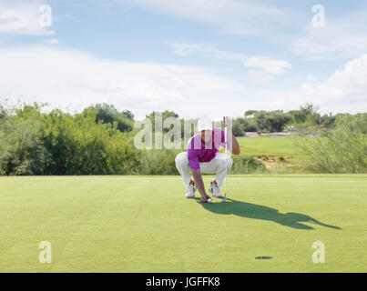 Golfista ispanica accovacciato sul campo da golf Foto Stock