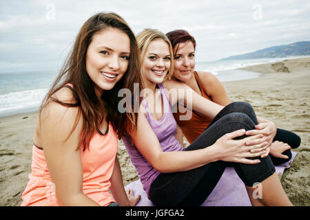 Ritratto di sorridente donne caucasici seduto sulla spiaggia Foto Stock