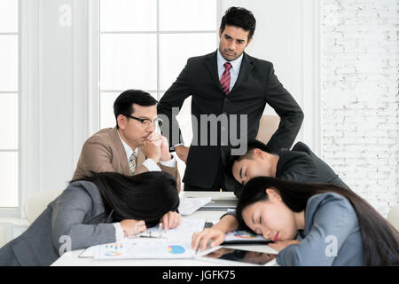 Boss arrabbiato quando la gente di affari di team di dormire sulla sala riunioni in ufficio. La gente di affari team stanco dopo il lavoro duro. Foto Stock