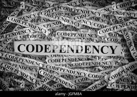 Codependency. Pezzi di carta strappati con le parole Codependency. Concetto di immagine. In bianco e nero. Primo piano. Foto Stock