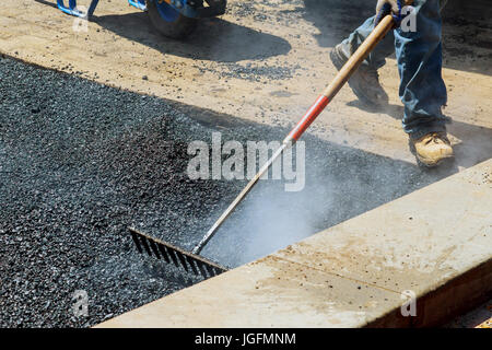 Lavoratori su asfaltatura lastricatore durante la strada lavori di riparazione. Street resurfacing. Asfalto fresco di costruzione. Cattiva strada Foto Stock