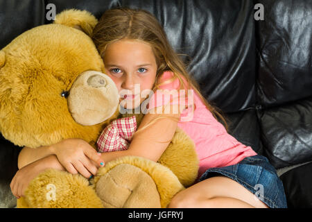 Giovane ragazza bionda abbracci orsacchiotto mentre sdraiato sul lettino Foto Stock